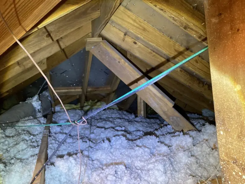 A restored attic with fresh insulation between the rafters